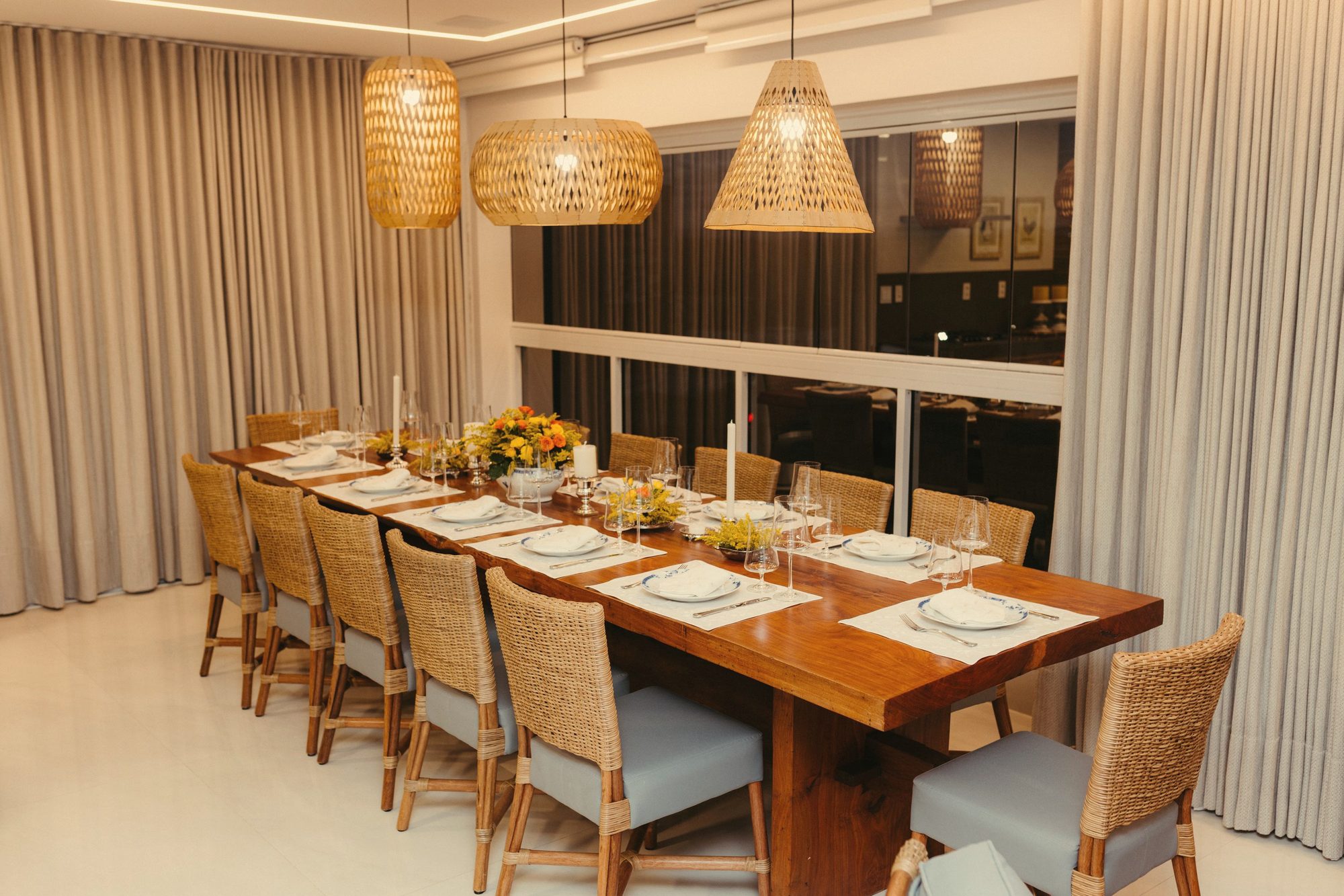 Long wooden dining table under woven pendants