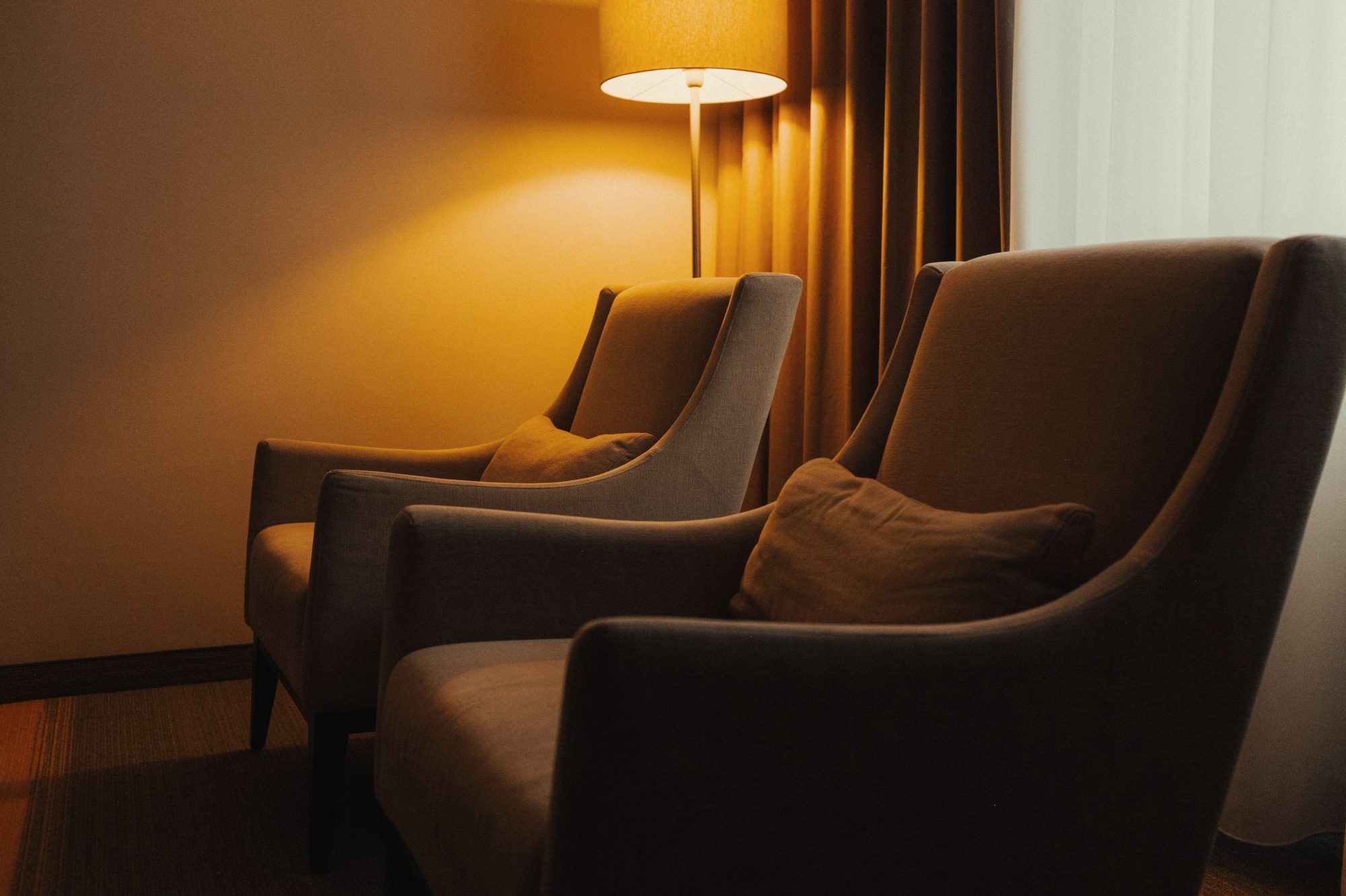 Armchairs by a glowing lamp at dusk