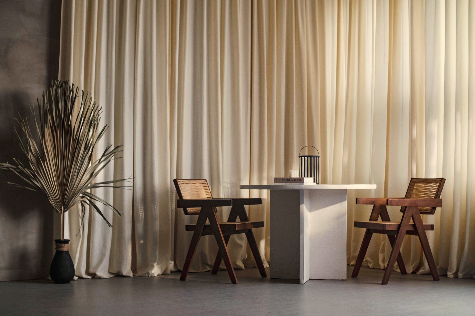 Cane chairs and a plinth table by cream curtains